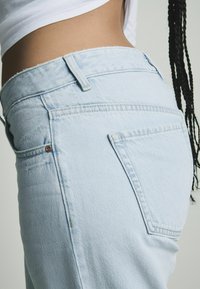 Lichtblauwe denim jeans met een licht verwassen tailleband, vijf-pocket ontwerp en een opvallend detail op de achterzak.
