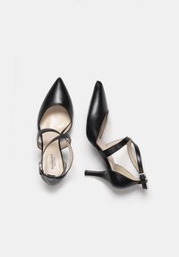 Chaussures à talons hauts en cuir noir avec des pointes effilées, des brides de cheville et un talon fin. La doublure intérieure est beige, avec une texture lisse.