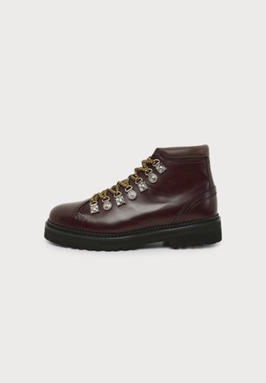 Dark brown leather hiking boot with thick black sole and yellow-brown laces threaded through silver metal hooks, shown in side profile.