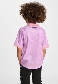 Lila sporttröja med strukturerat geometriskt mönster, gula och rosa accenter på kragen och ärmarna, märkt "INTERNATIONALS" på baksidan.