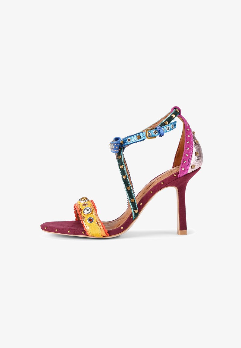 Wielokolorowe sandały na wysokim obcasie z materiału zamszowego, ozdobione dekoracyjnymi ćwiekami, z unikalnym wzorem paska w niebieskich, żółtych i fioletowych akcentach.
