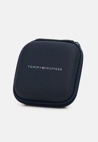 Navyblaues, mit Reißverschluss versehenes Etui mit einer glatten Textur. Auf der Vorderseite befindet sich das silberne Logo "TOMMY HILFIGER". Abgerundete Ecken und strapazierfähiges Material.