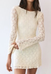 Robe mini en dentelle blanc cassé avec de longues manches évasées. Présente des motifs floraux et un ourlet festonné, mettant en valeur une silhouette ajustée.