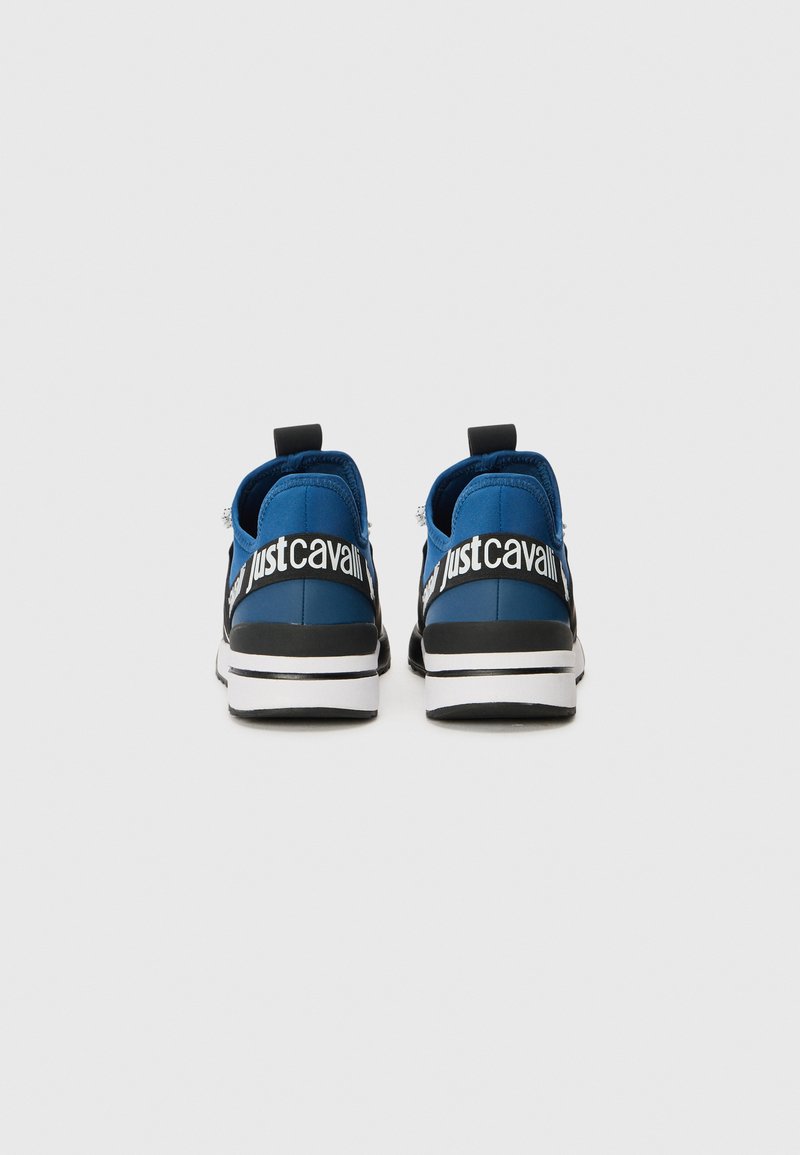 Niebiesko-czarne sneakersy z białymi podeszwami, widok z tyłu, z odważnym napisem "Just Cavalli" w białym kolorze na czarnych paskach.