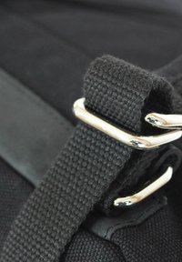 Schwarzer Stoffriemen mit einer silbernen Metallschnalle, die ein strukturiertes Gewebe und Lederakzente aufweist, was die langlebige Verarbeitung und die Designdetails betont.