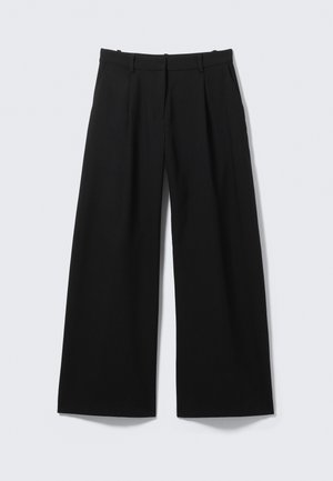 Pantalon à jambes larges en tissu noir uni, avec devant plat, plis et poches latérales. Matière légère à texture lisse.