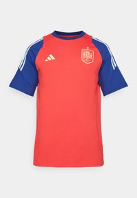 Punane ja sinine lühikeste varrukatega särk ümmarguse kaelusega, millel on bordüüritud Hispaania embleem ja kolm valget triipu varrukatel.