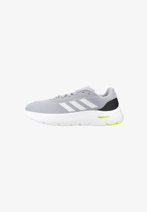 Zapatilla deportiva de malla gris claro con suela blanca, rayas blancas de Adidas en el lateral, acento negro en el talón y pequeña etiqueta amarilla "Cloudfoam Walk" en la suela.