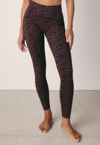 Des leggings taille haute en tissu extensible présentant un motif léopard brun et noir, conçus pour le confort et la liberté de mouvement.