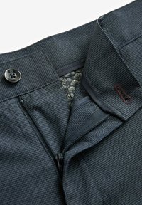 Marineblauwe geruite broek met een knoopsluiting en ritssluiting. Het interieur heeft een patroonvoering. Gemaakt van gestructureerde stof.