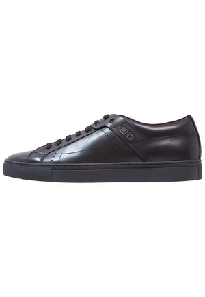 Black leather low-top sneaker with black laces, rubber sole, and subtle embossed brand logo on the side.