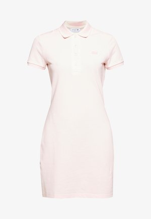 Vestuário de polo em algodão rosa claro, com colarinho, mangas curtas, pala de três botões e pequeno logo bordado no peito.