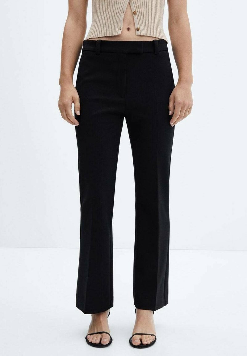 Czarne spodnie typu straight-leg o gładkiej teksturze, z paskiem w talii i prostymi liniami, w połączeniu z beżową prążkowaną bluzką do talii.