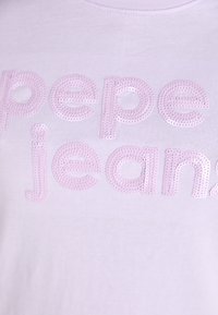 T-shirt violet clair avec le texte "pepe jeans" en sequins roses brillants ; design col rond avec une texture de tissu lisse.