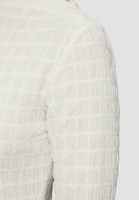 Tissu blanc texturé avec des rayures verticales, présentant un design plissé. Texture lisse avec une apparence légère et aérienne.
