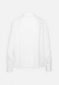 Blusa bianca a maniche lunghe con colletto, caratterizzata da una texture liscia, un taglio dritto e polsini bottonati, che presenta un design minimalista.