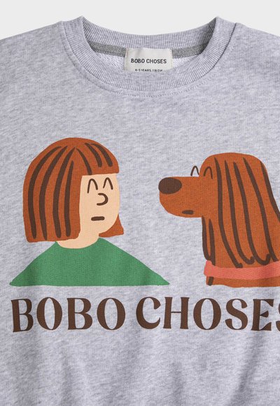 Grauer Pullover mit einem Cartoon einer Person mit braunen Haaren, die einen braunen Hund mit langen Ohren anschaut, darunter der Schriftzug "BOBO CHOSES".