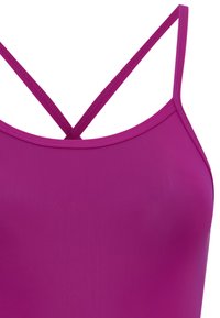 Le maillot de bain fuchsia présente des fines bretelles croisées, une texture lisse et une coupe ajustée. Le matériau semble extensible et léger.