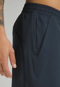 Shorts de sport navy avec une taille élastique, des poches latérales et un design texturé subtil le long des coutures.
