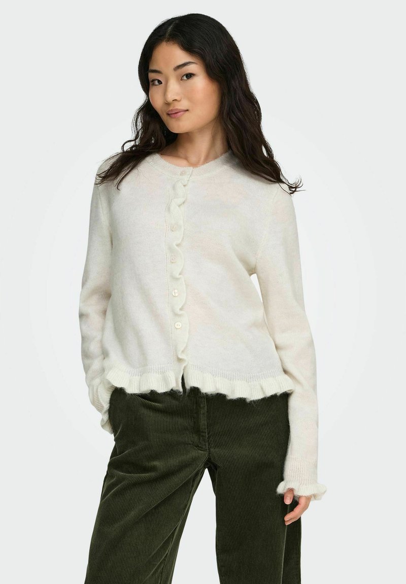 Cardigan color crema con bordo inferiore a scallop e polsini coordinati, caratterizzato da una fila di bottoni davanti, realizzato in morbido materiale lavorato a maglia.