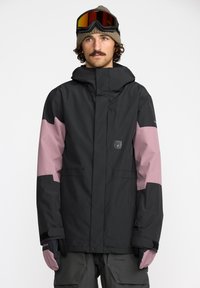 Veste de snowboard noire et rose avec capuche, présentant un design épuré, des poignets réglables et des poches. Accompagnée de gants et de lunettes.