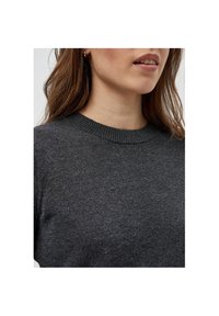 Mörkgrå stickad tröja med rund halsringning, slät textur och subtil glans. Närbild som fokuserar på tyget och detaljen vid halsen.