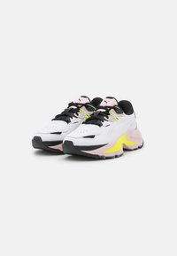 Białe i czarne sneakersy z żółtymi akcentami, strukturalną cholewką oraz różowymi detalami na języku i bokach, z dużą podeszwą.