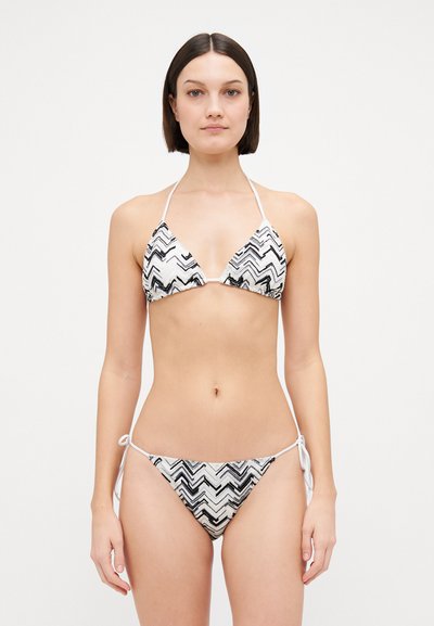 Bikini a zigzag bianco e nero, composto da un top triangolare e slip a vita bassa con lacci laterali, realizzato in un tessuto testurizzato.