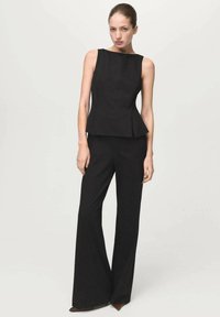 Haut péplum noir sans manches associé à un pantalon large assorti ; tissu lisse avec une coupe ajustée et des lignes épurées.