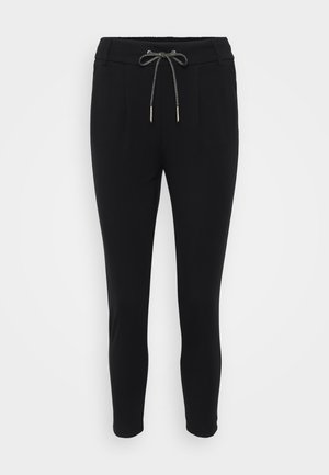 Melnas šauras bikses ar regulējamu jostas vietu, kurām ir divas priekšpuses kabatas un gluda, elastīga auduma tekstūra.