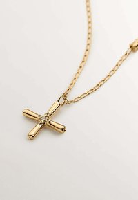 Collar de cadena de oro con un colgante de cruz pulido que tiene cuatro brazos y un embellecimiento central con pequeñas piedras claras.