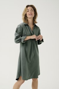 Groene jurk met kraag, lange mouwen opgerold en een ontspannen pasvorm. Glad stoftextuur met zijsplitten aan de zoom.
