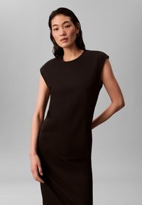 Svart, figursydd klänning med korta ärmar, rund halsringning och slät yta. Enkel, elegant design utan extra mönster eller detaljer.