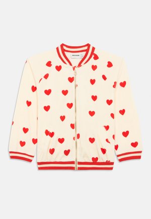 Κρέμ ζακέτα με φερμουάρ και κόκκινες καρδιές παντού, κόκκινο και κρέμ ριγωτό γιακά, μανσέτες και στρίφωμα, με δύο μπροστινές τσέπες.