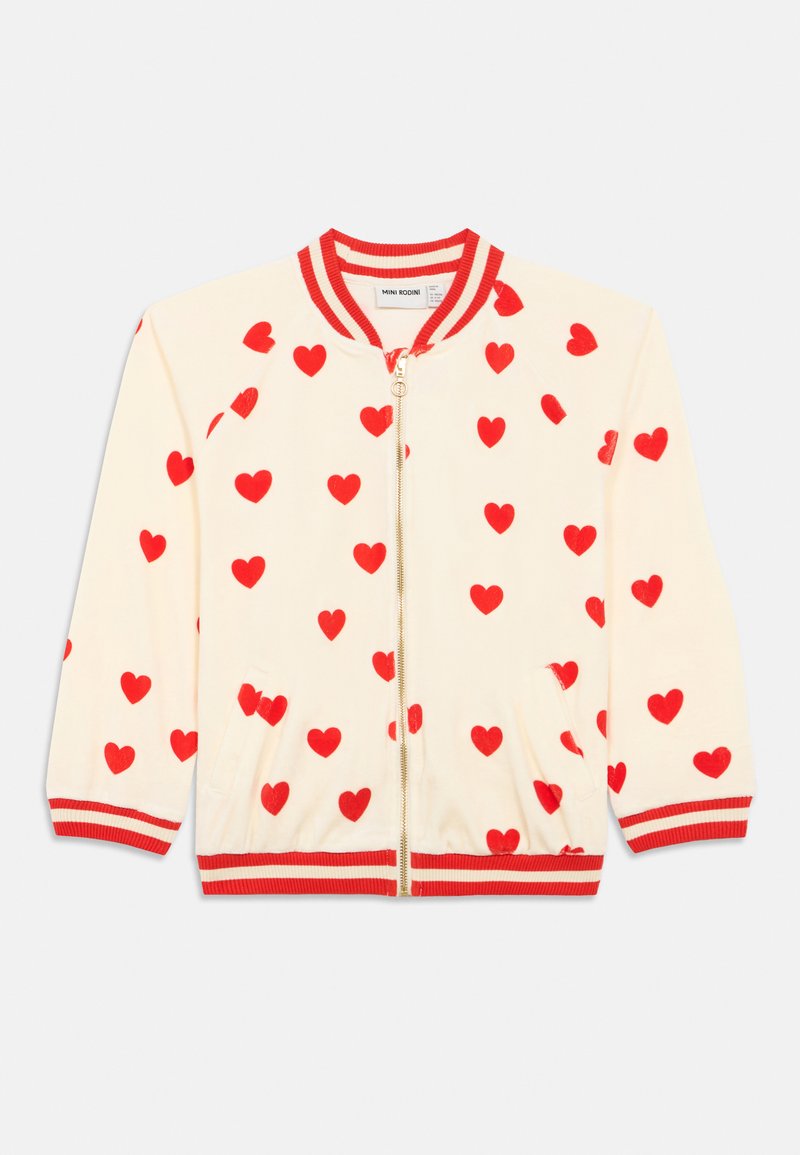 Chaqueta cremosa con cremallera y corazones rojos por toda la prenda, cuello, puños y dobladillo a rayas rojas y cremosas, y dos bolsillos frontales.