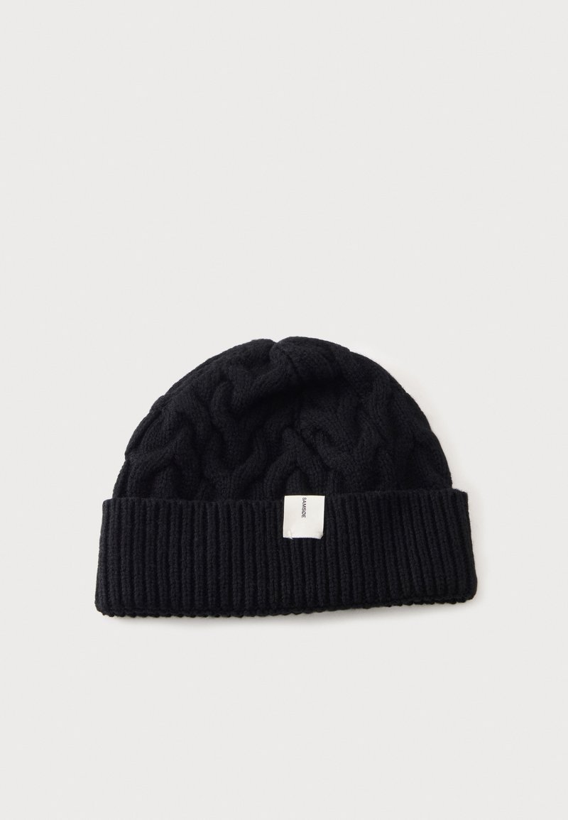 Bonnet noir en tricot avec un bord côtelé plié et une petite étiquette rectangulaire blanche au centre avant.