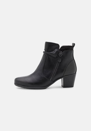 Bottines noires en cuir lisse, avec un bout arrondi, une fermeture éclair sur le côté et un talon épais. Accents texturés en haut.