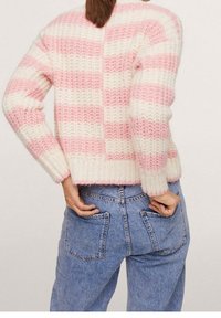 Neulepaita, jossa on vuorotellen vaaleanpunaisia ja kermajuovia, chunky-tekstuuri ja lyhyt malli. Yhdistetty korkeavyötäröisiin sinisiin farkkuihin.