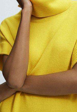 Gul stickad tröja med hög, ribbad polokrage och korta ärmar, som visar en mjuk textur och avslappnad passform.