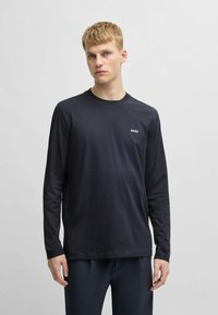 Black long-sleeve t-shirt in cotton with crew neckline. Features small white "BOSS" logo on left chest. Smooth texture with a relaxed fit.