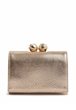 Pequeño bolso de piel granulada en tono dorado champán metalizado, con solapa y dos adornos esféricos dorados a modo de cierre, sobre fondo blanco.