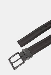 Cintura in pelle marrone con una texture liscia, caratterizzata da una fibbia in metallo lucido argentato e dal nome del marchio impresso sulla cinghia.