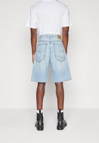 Ljusblå denimshorts med avslappnad passform, fem fickor och en märkesläderpatch. Bärs med svarta ankelstövlar och vita strumpor.