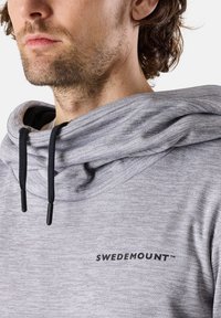 Felpa grigia con cappuccio ampio, dotata di cordini neri e una texture sottile. Il logo "SWEDEMOUNT™" è stampato sul petto.