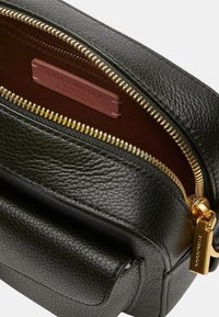 Borsa in pelle nera con finitura strutturata, dotata di una zip e accessori dorati, fodera interna rossa e etichetta del marchio all'interno.