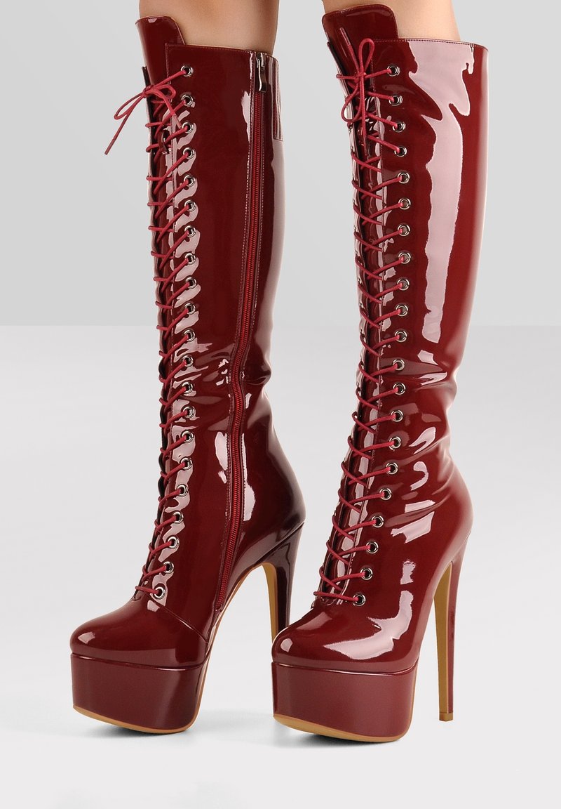 Bottes montantes en cuir verni bordeaux, à talons hauts, dotées d'un laçage sur le devant, d'une fermeture éclair latérale et d'une semelle plateforme.