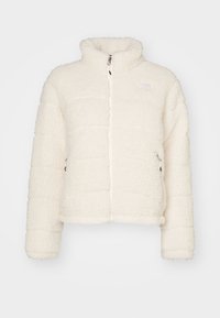 Biała polarowa kurtka z wysokim kołnierzem, zamek błyskawiczny i prążkowane mankiety. Posiada pikowaną teksturę oraz boczne kieszenie.