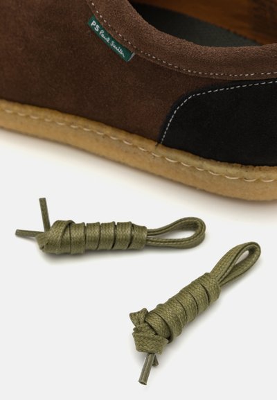 Brown suede shoe with black accents and a textured sole, paired with olive green braided laces with knotted ends, on a white background.
