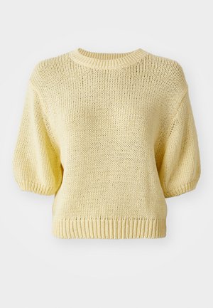 Kollane kudumisooversärk ümmarguse kaelusega, lühikeste puffvarrukatega ja soonikkantiga. Tekstuur on lahtine kudumine, mis annab juhusliku välimuse.