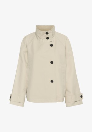 Beige jakk, mis on valmistatud pehmest kangast, millel on kõrge kaelus, kuus musta nööpi, küljetaskud ja sirge lõige koos üles keeratud varrukatega.